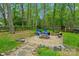Landscaped backyard with a stone fire pit area, surrounded by lush greenery and a wooden fence at 11700 Fernhurst Ln, Charlotte, NC 28277