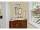 Charming bathroom vanity with a stone countertop, wood cabinet, mirror and bright natural light at 11700 Fernhurst Ln, Charlotte, NC 28277