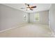 Bright bedroom with neutral walls, carpet, ceiling fan, and windows offering views of the surrounding area at 11700 Fernhurst Ln, Charlotte, NC 28277