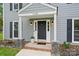 Close-up of the front door, sidelights, brickwork, and covered entrance, accented with flowers and stone pillars at 11700 Fernhurst Ln, Charlotte, NC 28277