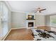 Bright living room featuring a white-painted fireplace with a rustic wood mantel, wood floors, and a ceiling fan at 11700 Fernhurst Ln, Charlotte, NC 28277