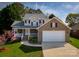 Charming two-story home with a brick facade, covered porch, manicured lawn, and attached two-car garage at 121 Shagbark Ln, Mooresville, NC 28115