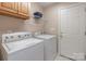 Bright laundry room features modern washer and dryer, overhead cabinet, and access door at 121 Shagbark Ln, Mooresville, NC 28115