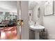 Half bathroom with a pedestal sink, oval mirror and a peek into the living room at 12905 Bullock Greenway Blvd, Charlotte, NC 28277