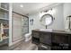 Modern bathroom features a glass-enclosed shower, rustic vanity, and eye-catching round mirror with unique light fixture at 141 Forsythia Ln, Tega Cay, SC 29708