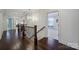 Bright hallway boasts gleaming hardwood floors, decorative railing, and modern chandelier lighting at 141 Forsythia Ln, Tega Cay, SC 29708