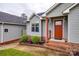 Inviting front entrance with brick steps, red door, manicured landscaping, and light green siding at 1545 Wimbleton Woods Dr, Fort Mill, SC 29708