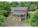 Aerial shot of a brick home with a sunroom, manicured lawn, mature trees, and paved driveway, showcasing curb appeal at 203 Mt Holly Huntersville Rd, Huntersville, NC 28078