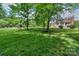 Large grassy backyard with mature trees, featuring a playground, and offering ample space for outdoor activities at 203 Mt Holly Huntersville Rd, Huntersville, NC 28078