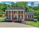 Classic brick home with a charming front porch, rocking chairs, and manicured landscaping at 203 Mt Holly Huntersville Rd, Huntersville, NC 28078