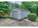 Exterior view of a detached one-car garage with white siding and concrete driveway, set amongst mature landscaping at 203 Mt Holly Huntersville Rd, Huntersville, NC 28078