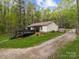 View of the backyard, showcasing the deck, mature trees, and gravel driveway at 214 Creek View Rd, Mooresville, NC 28117