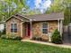 Close-up of a single-story home with a stone facade, manicured landscaping, and a bright red front door at 214 Creek View Rd, Mooresville, NC 28117