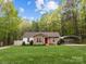 Charming single-story home featuring a stone facade, bright red door, carport, and lush green lawn at 214 Creek View Rd, Mooresville, NC 28117