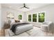 Staged bedroom featuring hardwood floors, three large windows, a ceiling fan, and modern decor at 2512 Remington St, Charlotte, NC 28216