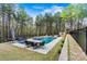 Outdoor pool area with a dining table, lounge furniture, and surrounded by a privacy fence and mature trees at 3207 Oak Ridge Cir, Lincolnton, NC 28092