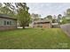 Spacious backyard with grassy area and mature trees, brick house and fenced in yard at 3701 Slagle Dr, Charlotte, NC 28215