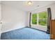 Cozy bedroom with a window overlooking trees, showcasing a simple design with blue carpet and white walls at 380 Hamrick Rd # 1, Gastonia, NC 28056