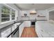 Bright kitchen featuring white cabinets, black countertops, stainless steel appliances, and wood floors at 4205 Cahnnas Way, Waxhaw, NC 28173