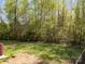 Large backyard with lush lawn and mature trees surrounded by a black metal fence at 428 Winecoff Woods Nw Dr, Concord, NC 28027