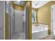 Bright bathroom featuring a glass enclosed shower and separate soaking tub with decorative tile accents at 428 Winecoff Woods Nw Dr, Concord, NC 28027