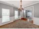 Open-concept dining area featuring neutral carpeting, gray walls, white wainscoting, and a decorative chandelier at 431 Harvest Ter, Lake Wylie, SC 29710