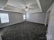 Spacious main bedroom showcasing plush carpet, a tray ceiling with fan, and bright windows at 5025 Wicklow Dr, Gastonia, NC 28054