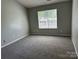 Neutral bedroom featuring gray walls, plush carpeting, and natural light from a window at 6239 Burmith Ave, Charlotte, NC 28269
