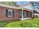 Close up of a red brick home featuring a front porch, black shutters, and a well maintained green lawn at 6549 Wesbrook Dr, Charlotte, NC 28214