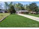 A brick home with a well-kept lawn and a long driveway leading to a one-car garage on a sunny day at 6549 Wesbrook Dr, Charlotte, NC 28214