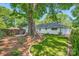 Landscaped backyard with green grass, plants, a brick patio, a dark fence, and a large tree providing plenty of shade at 700 Cooper Dr, Charlotte, NC 28210