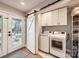 Efficient laundry room with white cabinets, sliding barn door, and modern appliances, offering convenience and ample storage at 700 Cooper Dr, Charlotte, NC 28210