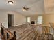 Open-concept living room with a fireplace, ceiling fan, and wood floors, creating a warm ambiance at 7154 Woodcock Trl, Stanley, NC 28164