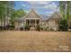 View of the home's brick exterior, covered patio, and spacious backyard with an outdoor dining set at 7982 Buena Vista Dr, Denver, NC 28037
