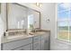 Well-lit bathroom with dual sinks, light gray cabinetry, a large mirror, and a window providing natural light at 9914 Ainslie Downs St, Charlotte, NC 28273