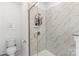 Modern shower with sleek glass door and marble-patterned tile, equipped with built-in shelving at 9914 Ainslie Downs St, Charlotte, NC 28273