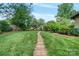 Landscaped backyard with a brick walkway leading to a greenhouse at 10315 Washam Potts Rd, Cornelius, NC 28031