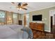 Spacious bedroom featuring hardwood floors, ceiling fan, and a TV on a wooden dresser at 10315 Washam Potts Rd, Cornelius, NC 28031