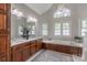 Bright bathroom with double vanity, soaking tub, chandelier, and beautiful natural light from multiple windows at 1176 Fawn Ridge Nw Rd, Concord, NC 28027