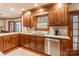 Traditional kitchen with wood cabinets, stainless steel dishwasher, and views of the backyard at 1176 Fawn Ridge Nw Rd, Concord, NC 28027
