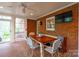 Cozy brick sunroom featuring comfortable bench seating, dining table, and TV at 1176 Fawn Ridge Nw Rd, Concord, NC 28027