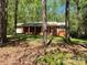 Single-story brick home with a covered front porch and lush green lawn surrounded by trees at 1199 Riding Trail Ln, Concord, NC 28027