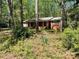 Charming single-story home with a covered front porch nestled amongst mature trees and natural landscaping at 1199 Riding Trail Ln, Concord, NC 28027