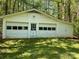 A detached two-car garage with an overhead door and a side entrance, set amongst mature trees at 1199 Riding Trail Ln, Concord, NC 28027