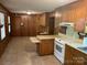 Vintage eat-in kitchen features wood-paneled walls and matching cabinets and tile floor at 1199 Riding Trail Ln, Concord, NC 28027
