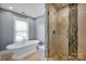 Bright bathroom featuring a standalone tub and separate shower with decorative tile at 12932 Westmoreland Farm Rd, Davidson, NC 28036
