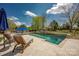 Inviting backyard pool with stone surround, outdoor fireplace, and lounge chairs offers a relaxing oasis at 12932 Westmoreland Farm Rd, Davidson, NC 28036
