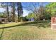 View of the expansive backyard featuring multiple storage sheds surrounded by verdant lawn and mature trees at 1315 Arbor Dr, Salisbury, NC 28144