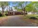 Single-story brick home on a lot with established trees and a gravel driveway at 1315 Arbor Dr, Salisbury, NC 28144