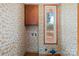 Laundry room featuring wood-look wallpaper, a cabinet, a window and vintage flooring at 1315 Arbor Dr, Salisbury, NC 28144